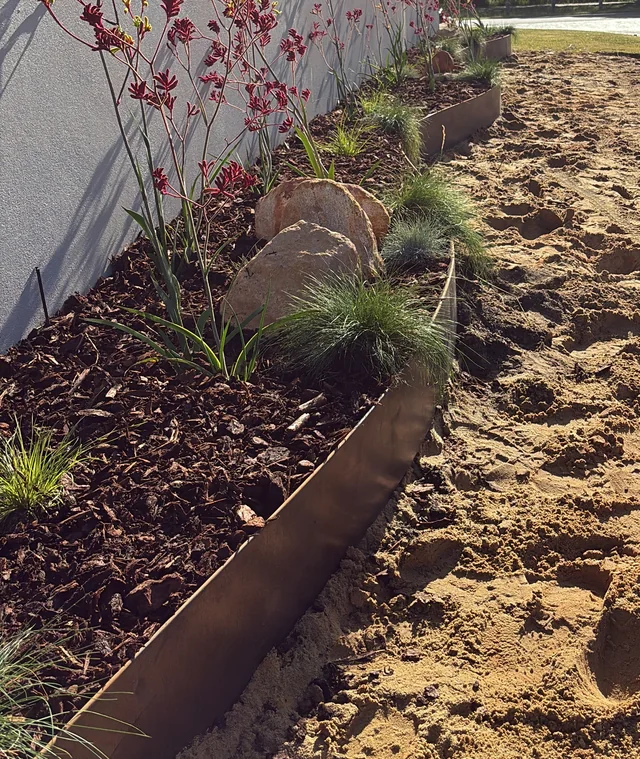 Curved steel edging beside a landscaped lawn and garden bed