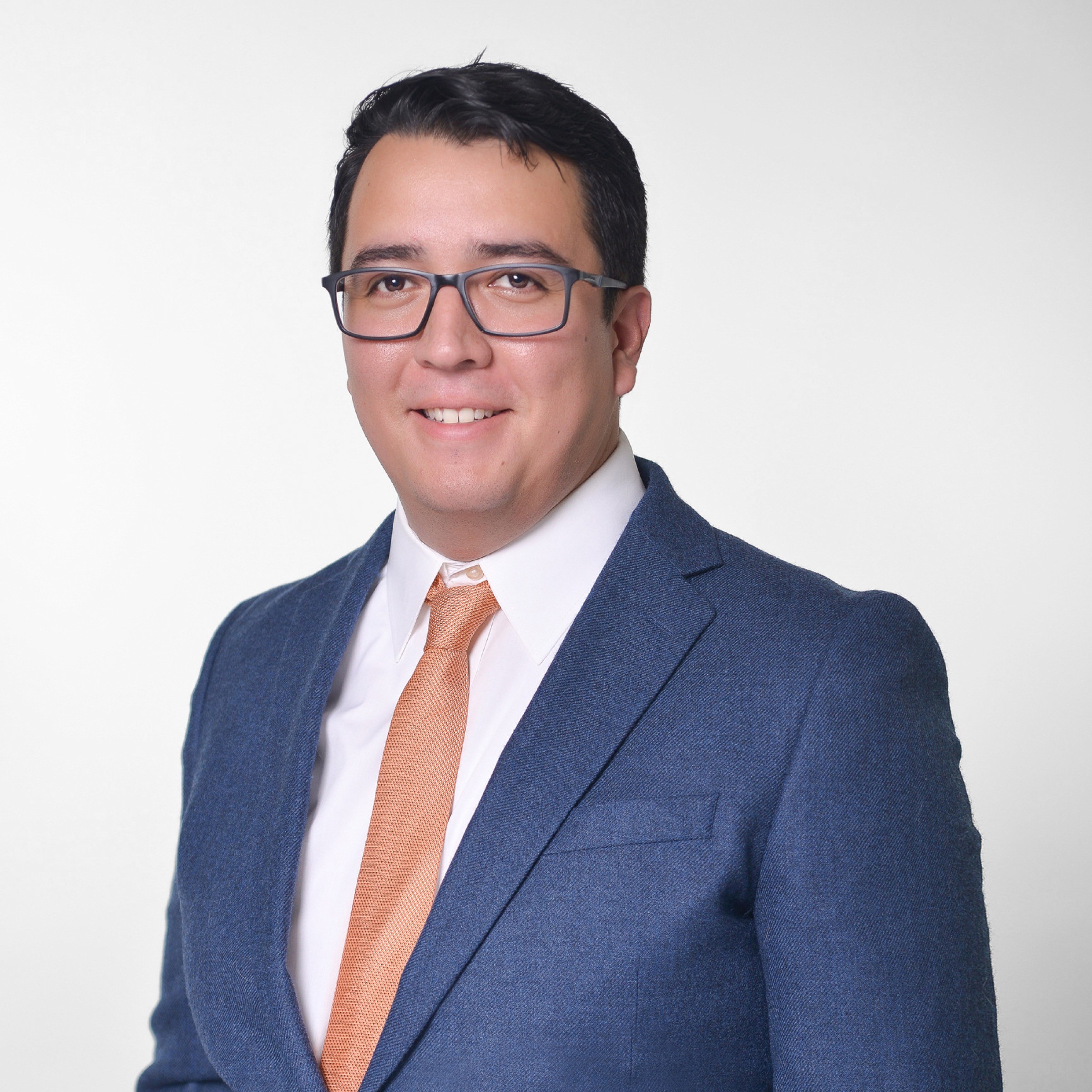 Professional studio headshot of a man in a blue suit
