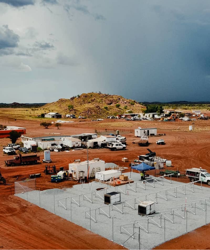 Construction of a renewable energy system in a remote, arid Australian landscape with a storm approaching.