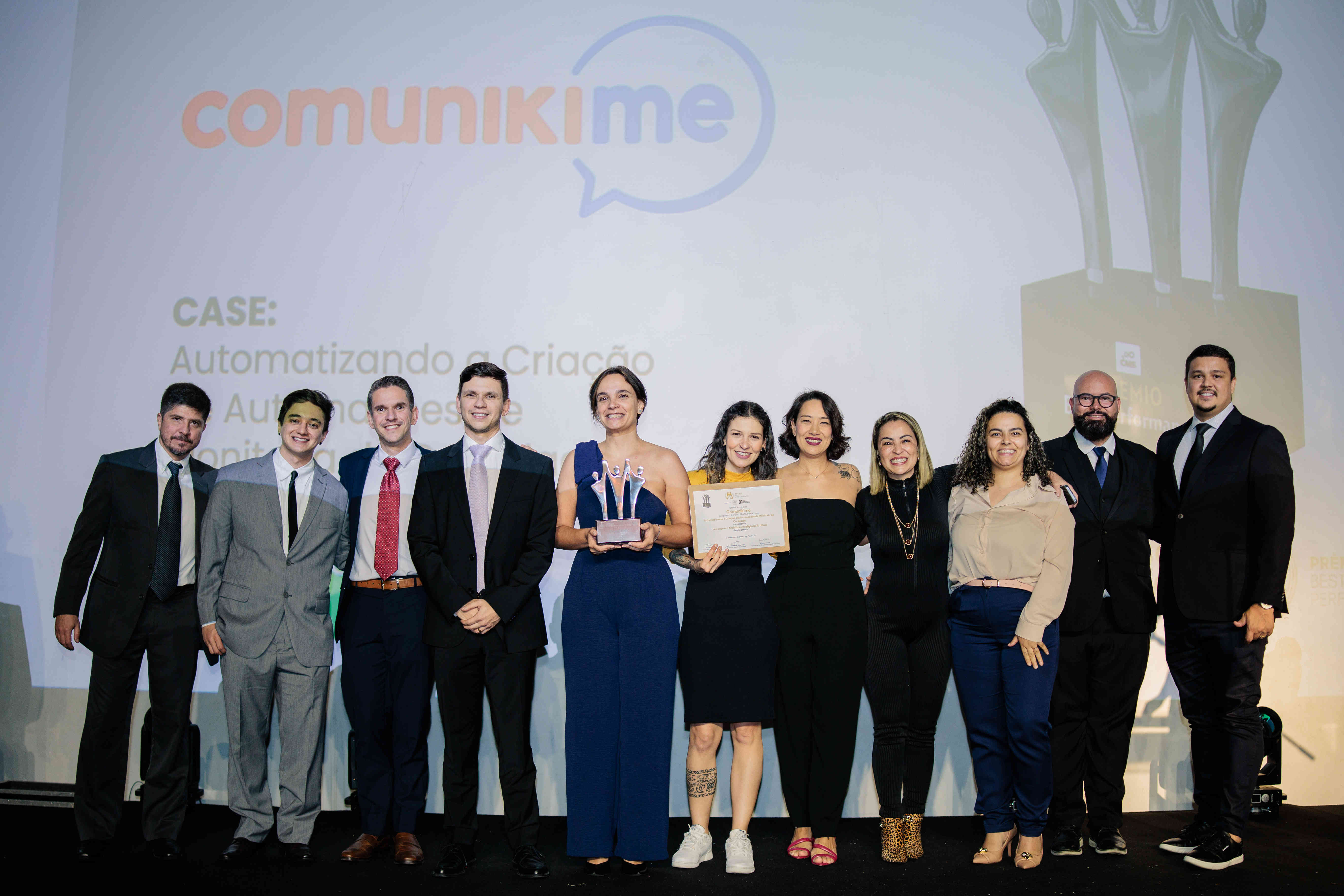 Executivos da Comunikime posando com troféu prata e certificado no palco do Prêmio Best Performance 2025