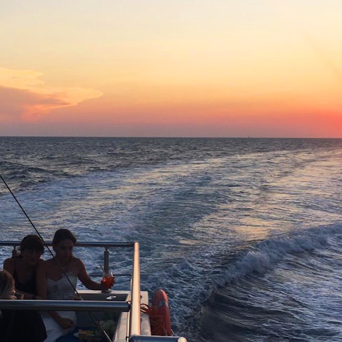 Lidé si užívají nápoj a pohled z lodi.