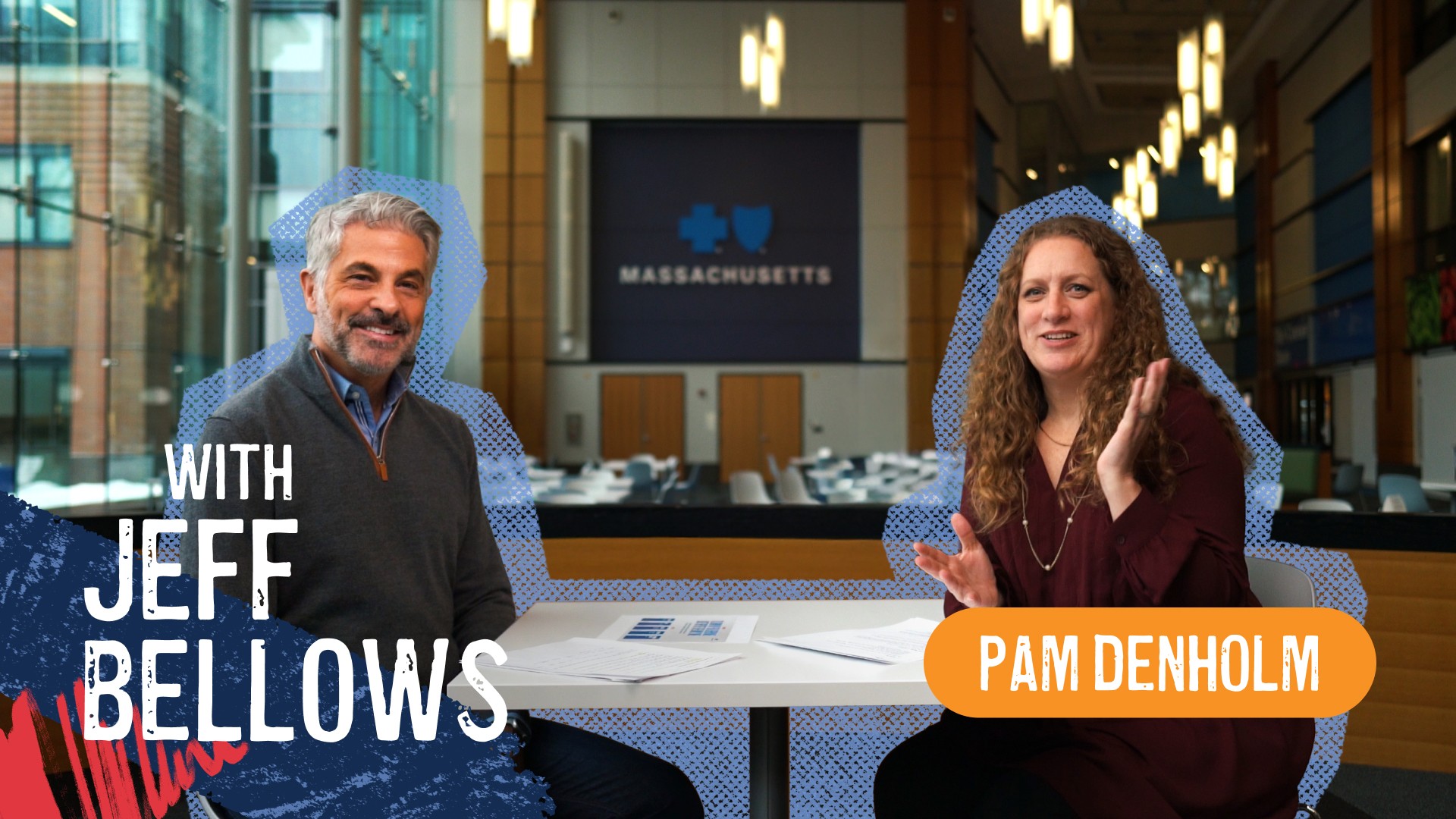 A woman wearing glasses smiles in a warehouse setting; the logo on her vest reads “The Greater FOOD BANK” and “TEAM GFB.”
