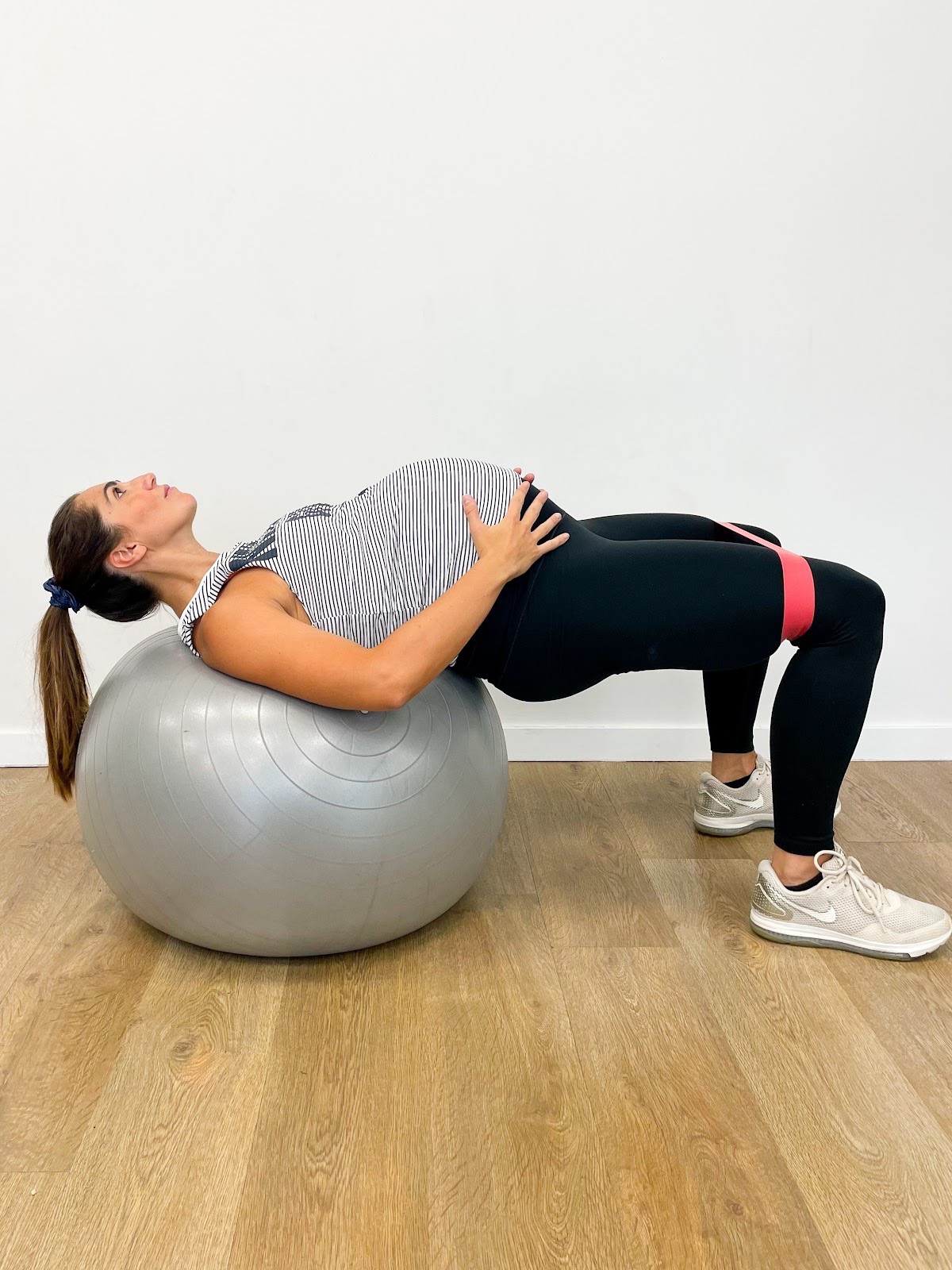 Femme enceinte faisant un exercice de fitness avec un ballon de grossesse pour muscler ses fessiers.