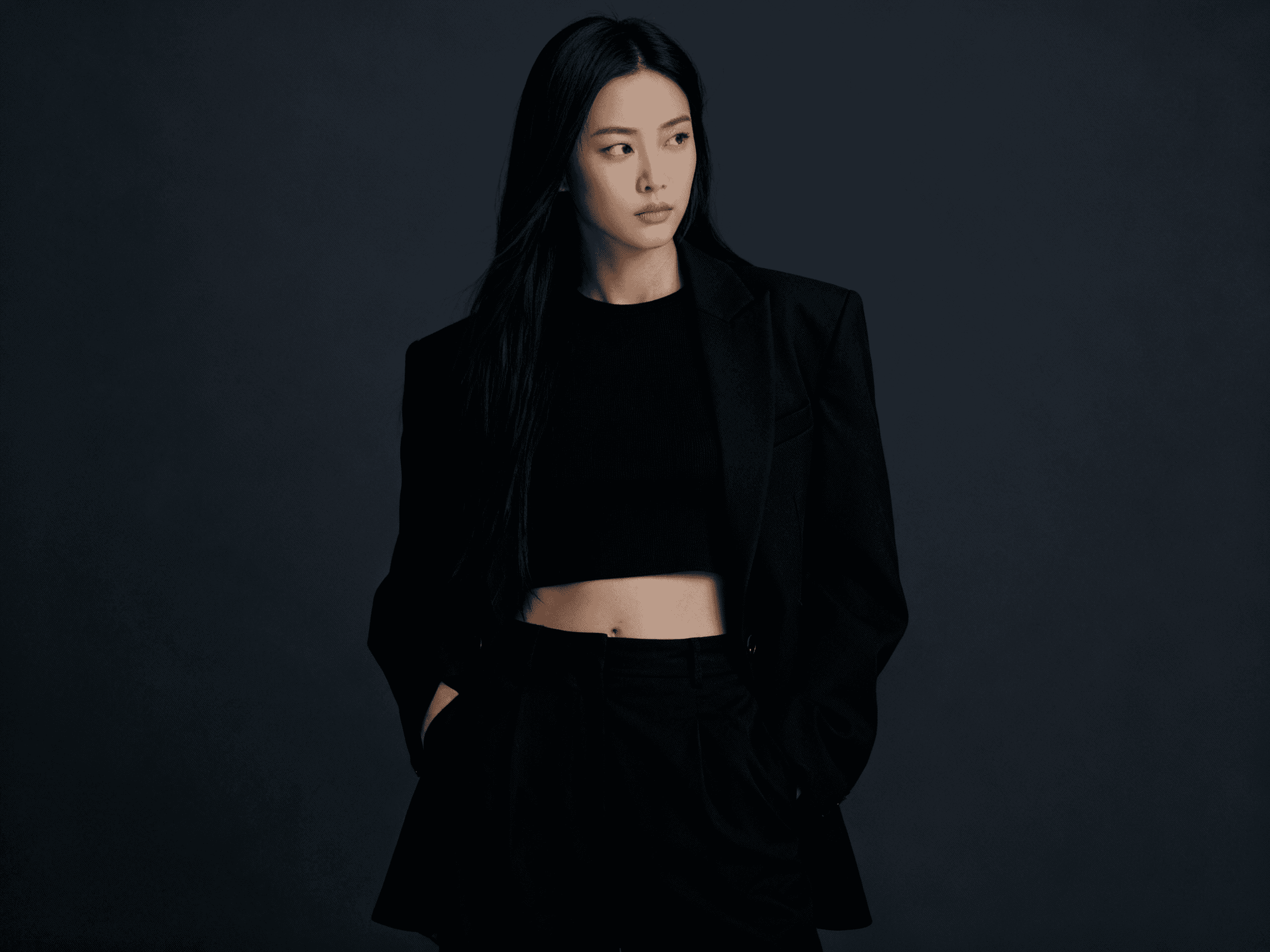 Minimalist facade with red window and striped awning on a white stucco wall under a clear blue sky.
