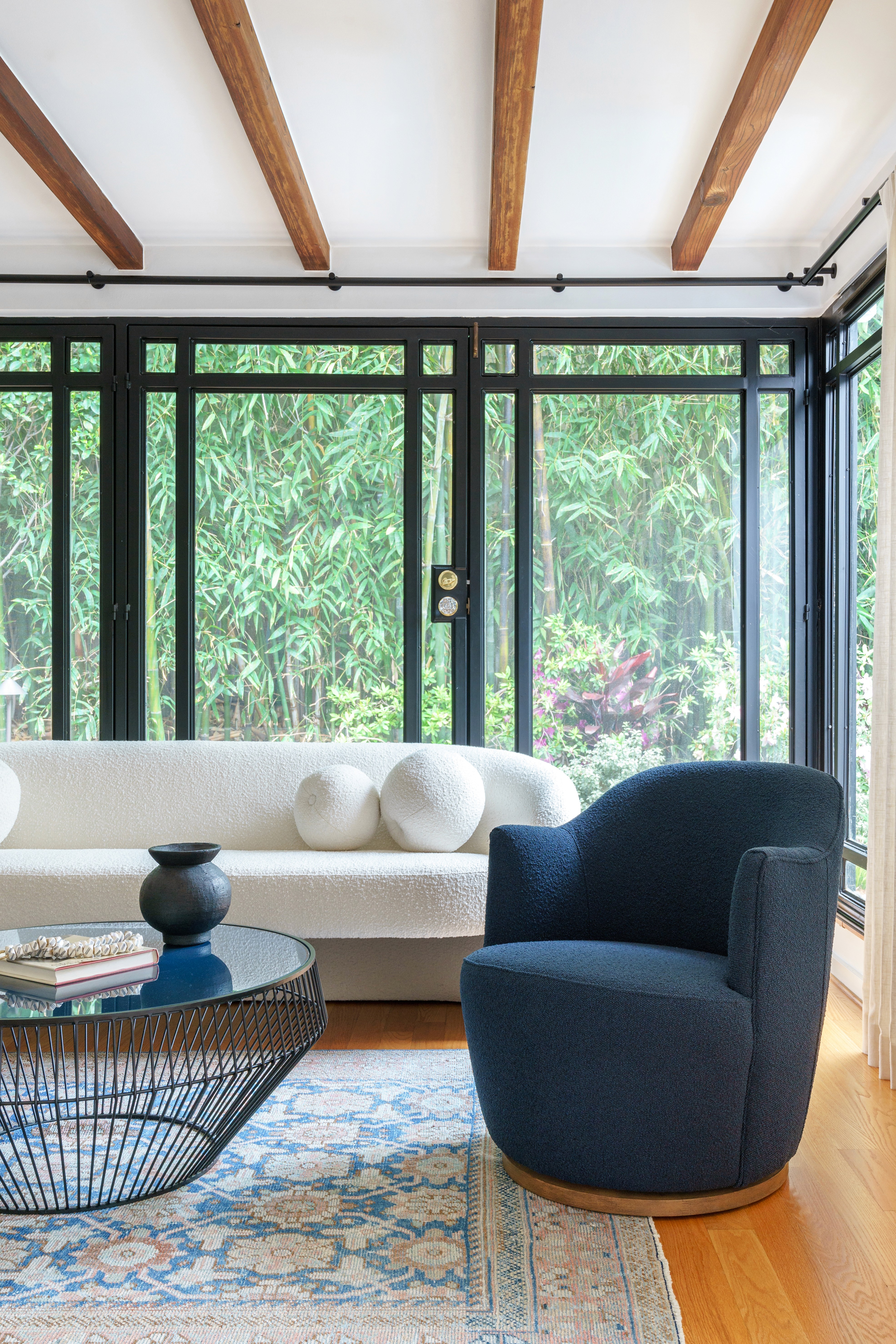 Sun beds with linen upholstery and accent pillows, complemented by stone, wood, and metal accents, create an elegant seating arrangement