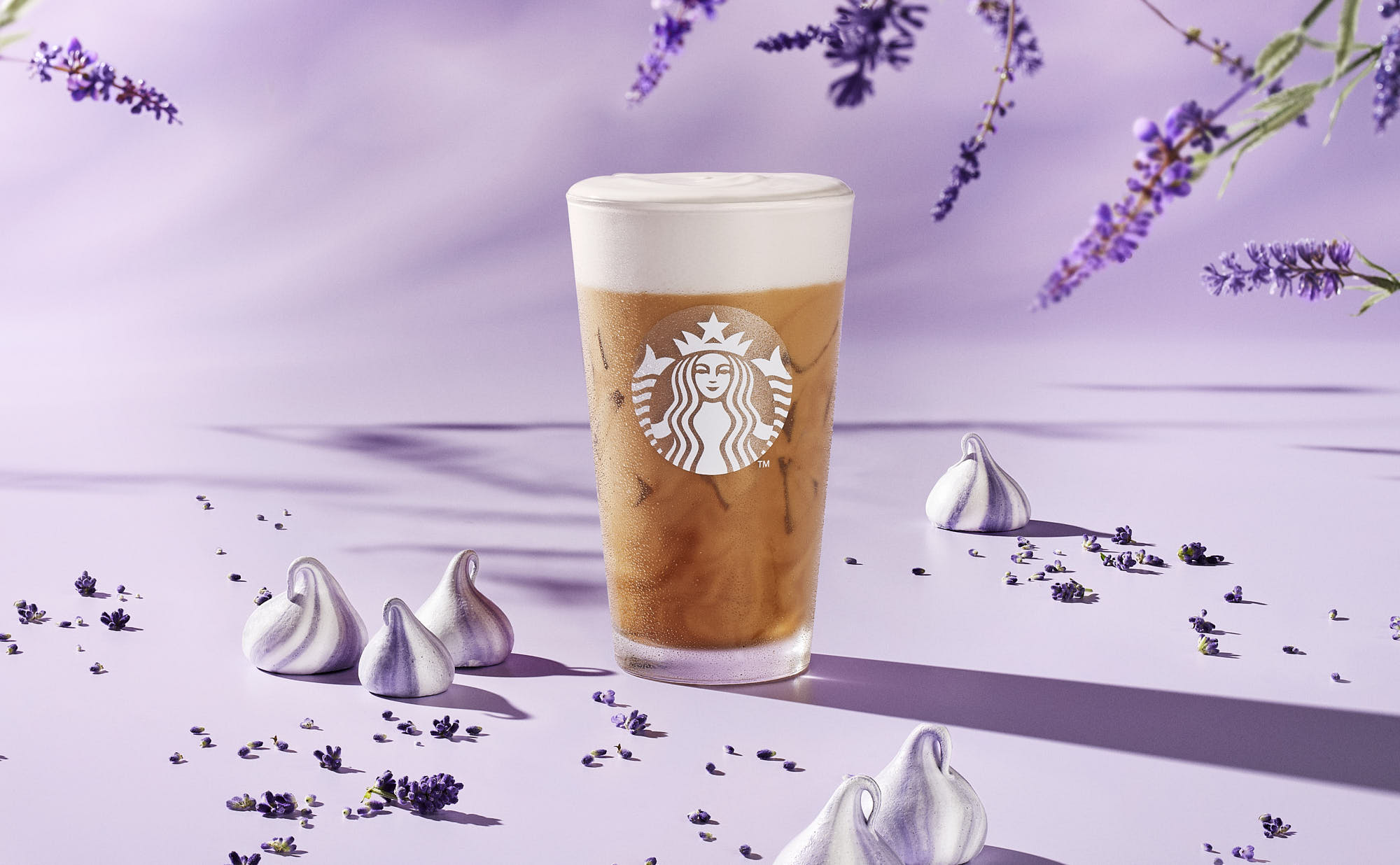 A container of beverage sits on a snowy landscape with purple mountains in the background.