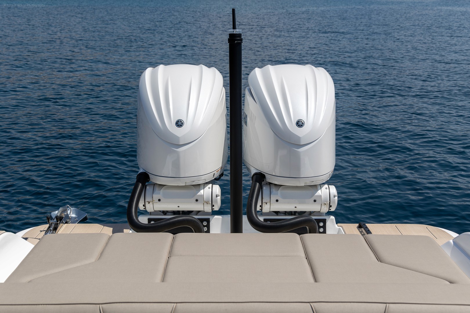 Twin white outboard motors mounted on the stern of Rock 36 Naboo yacht with calm blue Aegean waters in background.