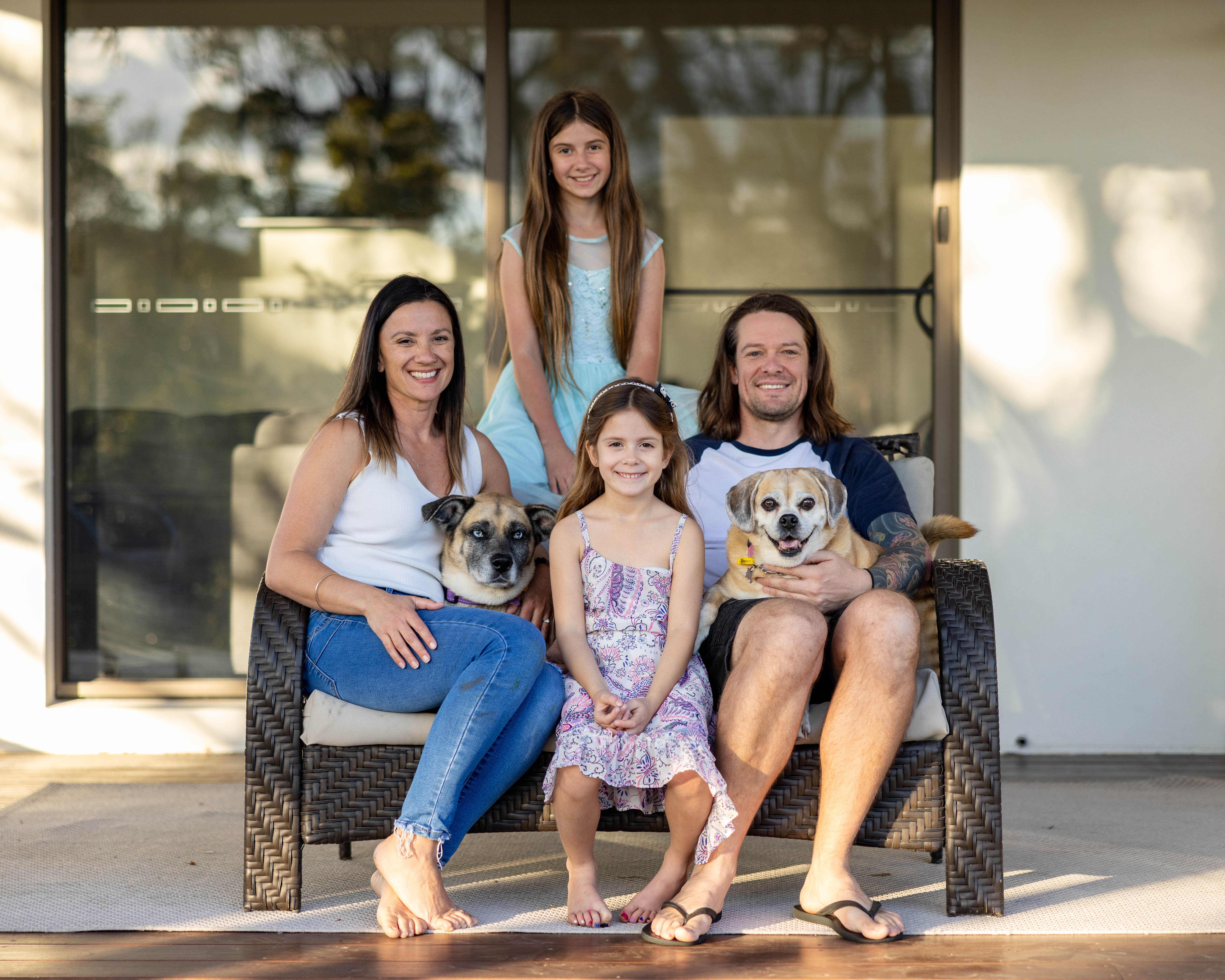 Portrait of young family and two dogs on deck of house