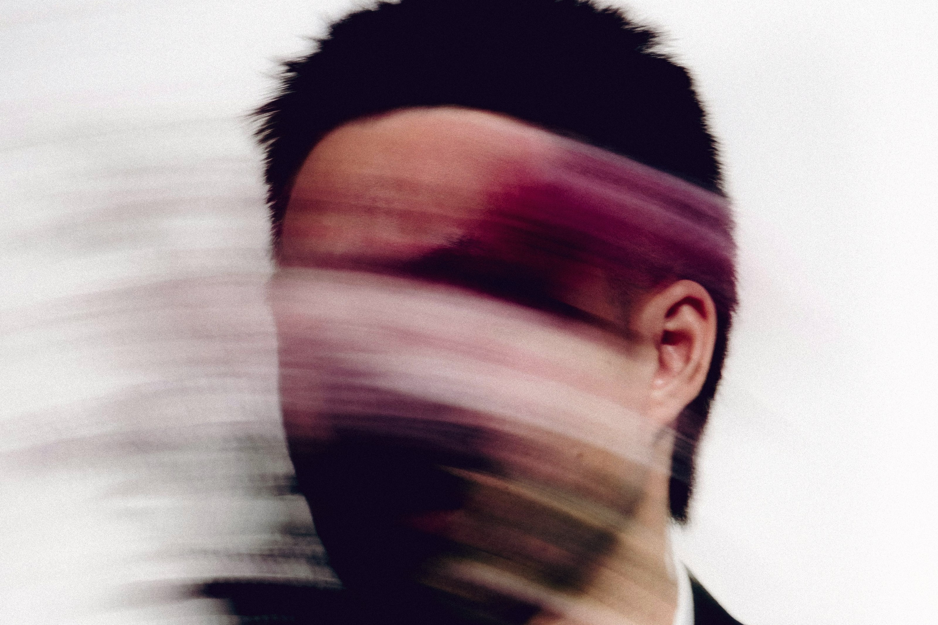 A man in a dark suit caught mid-motion, his face blurred into streaks of magenta