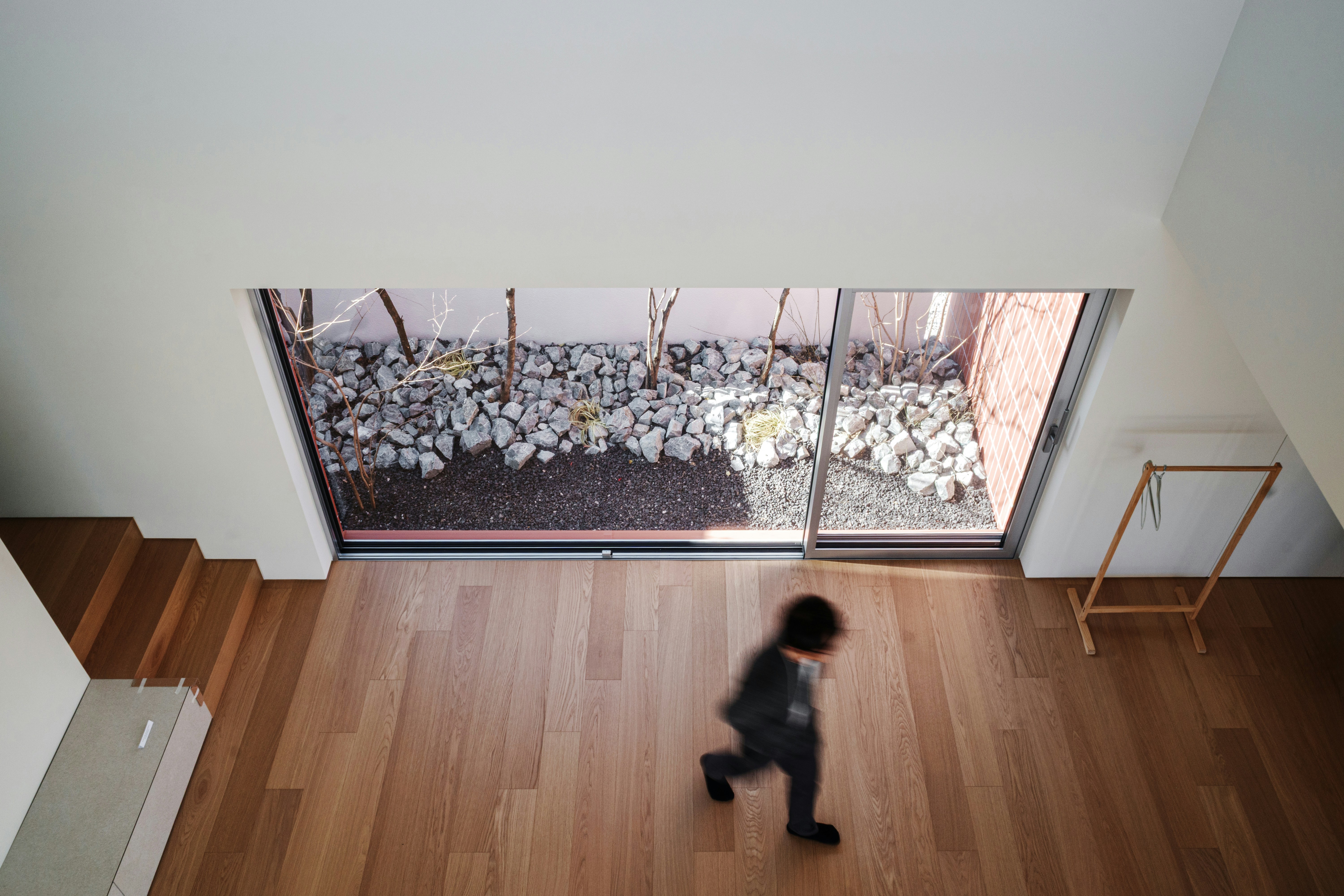 Child running across a wooden floor near a window.