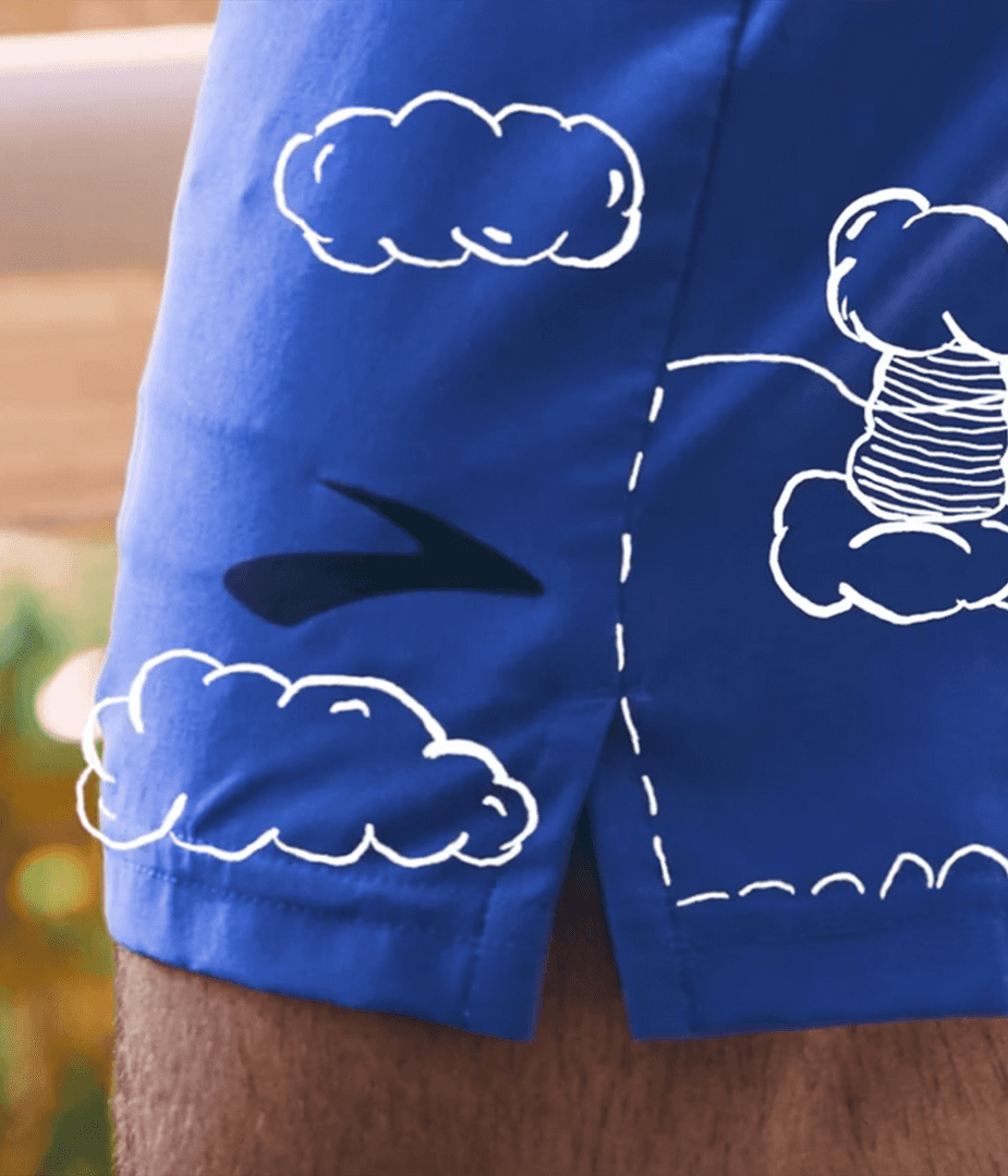 Close-up of blue Brooks running shorts with white hand-drawn clouds and thread animation, visualizing comfort and lightweight performance.