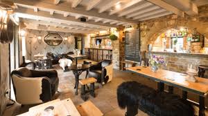 Rustic country pub interior with exposed wooden beams, stone walls and cozy dining area, traditional British inn atmosphere