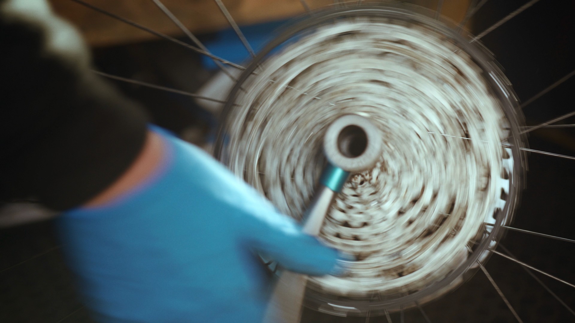 Close-up of a mechanic working on a bicycle's rear cassette and drivetrain during a mobile bike servicing session.