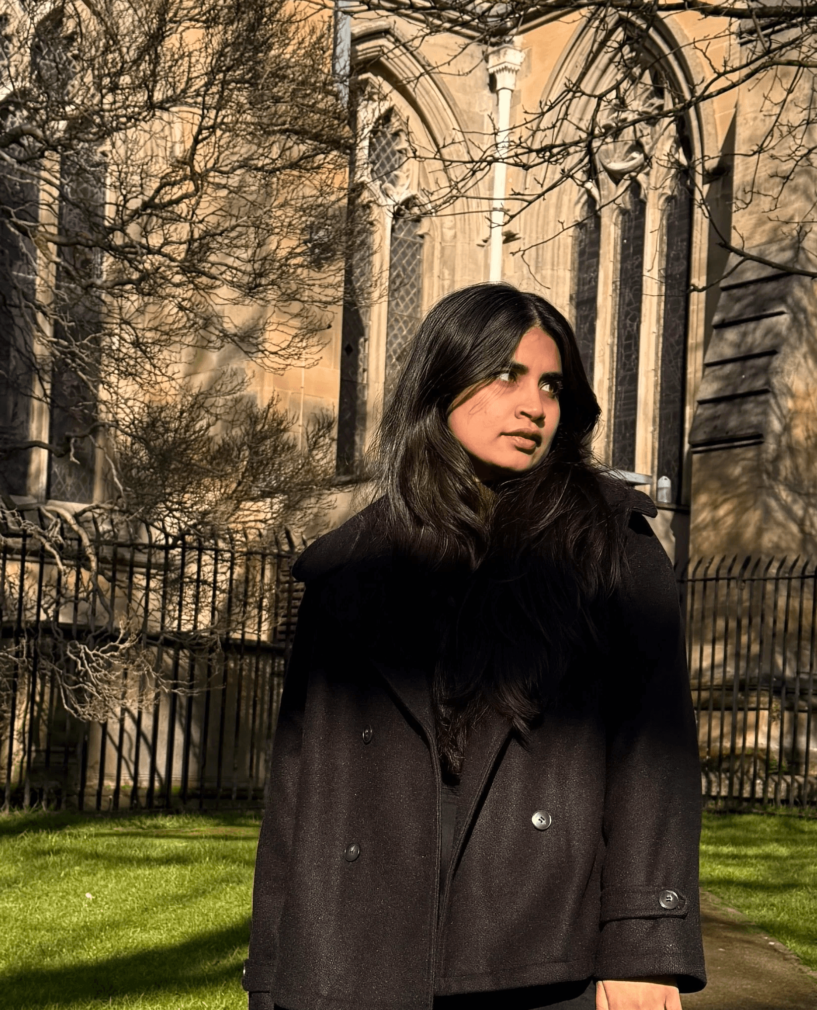 A thoughtful young person with dark hair gazes to the side, captured in soft black and white lighting.