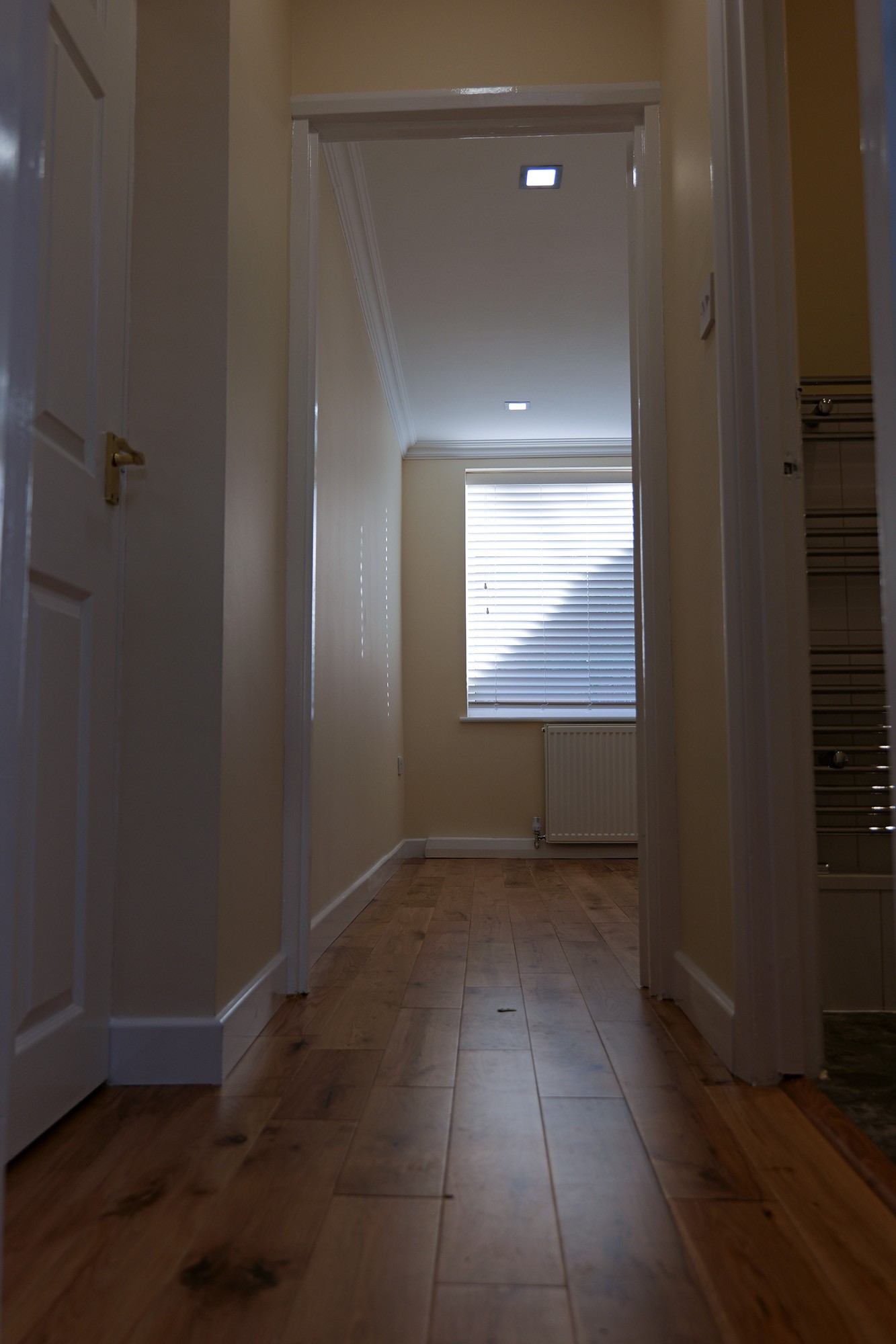 Looking down the corridor separating two rooms with window at the end of the room