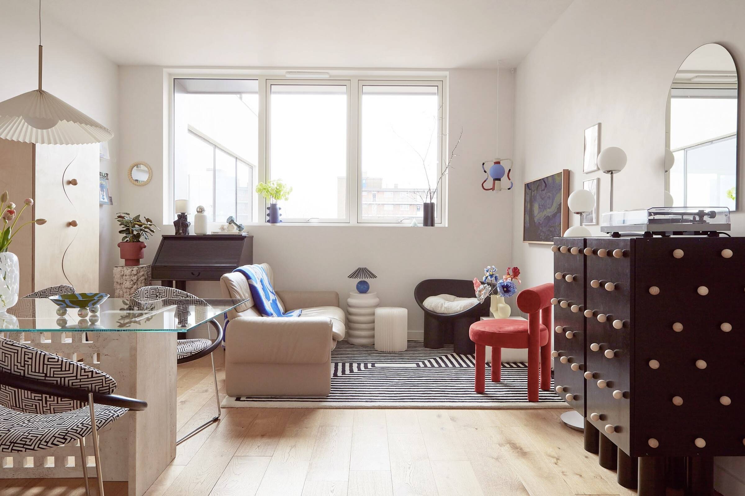 Bright, playful living room interior with layered furniture, bold accents and natural light, designed by Atelier Akuko