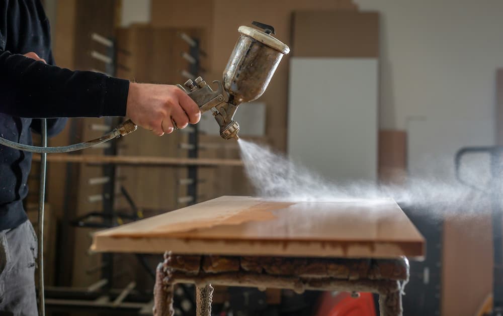 Carpenter spraying wood