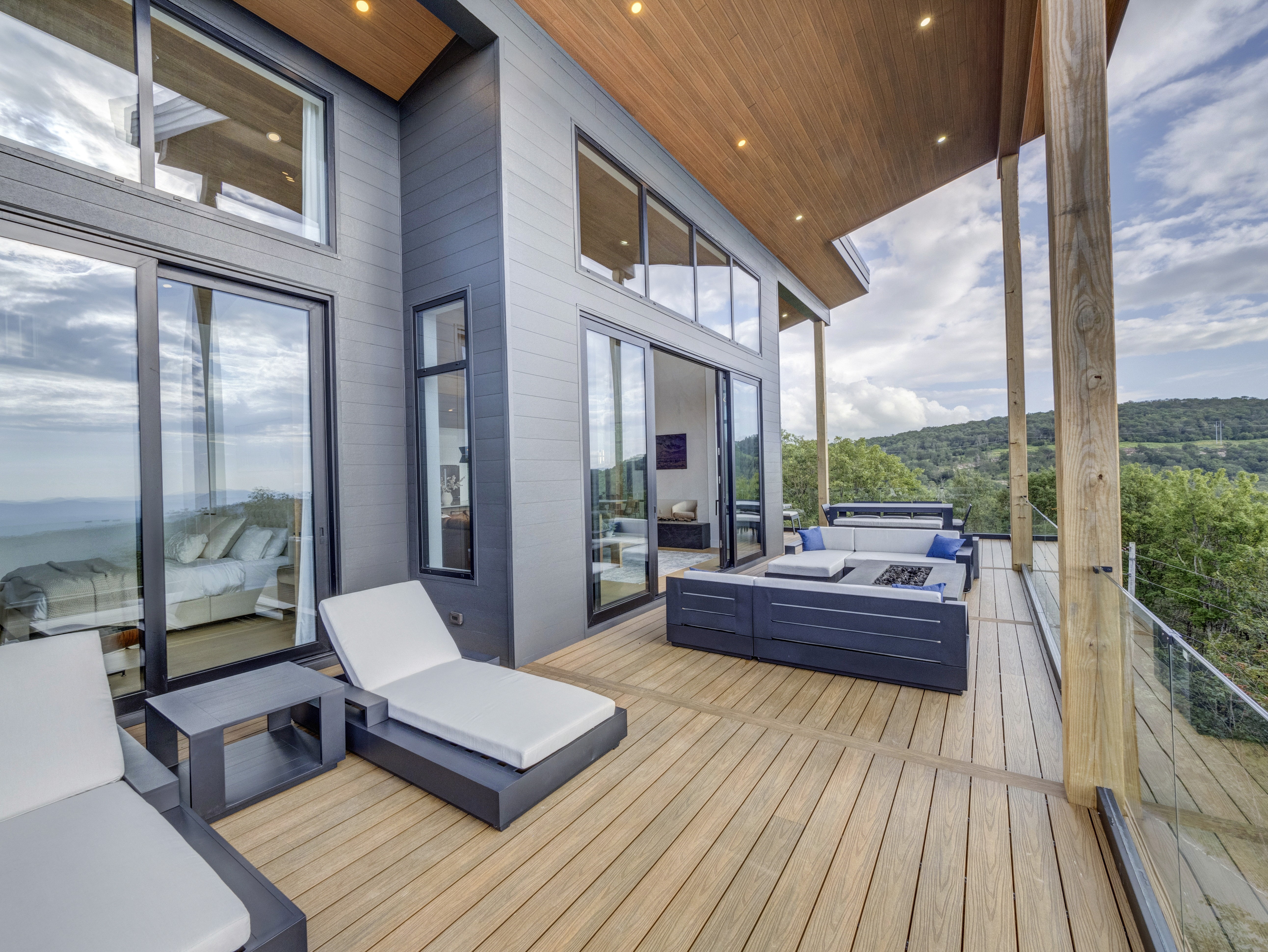 Architectural exterior of a grey modern home with large glass windows, showing the seamless flow of the wrap-around deck