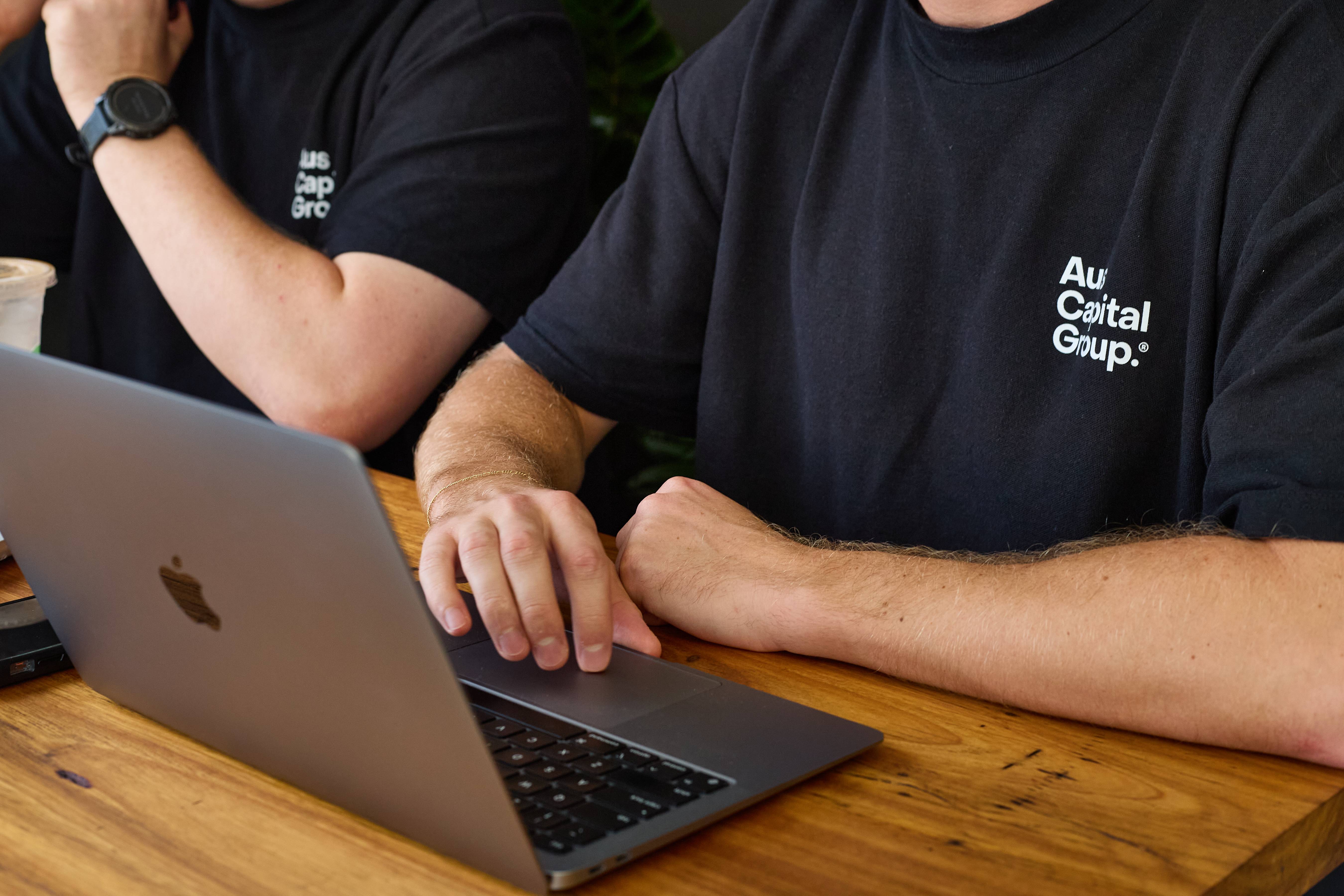 Woman in blue hat and sweater sitting on couch with laptop.