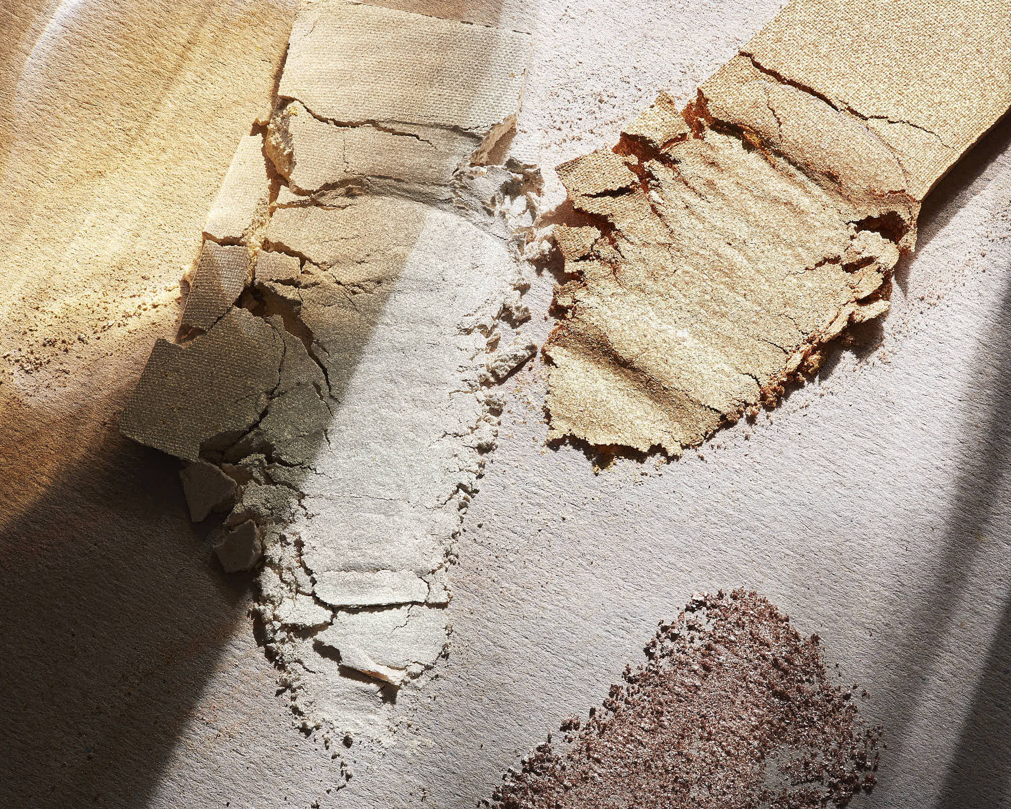 A close-up of a broken cosmetic powders resting on a light-colored surface with visible textures.