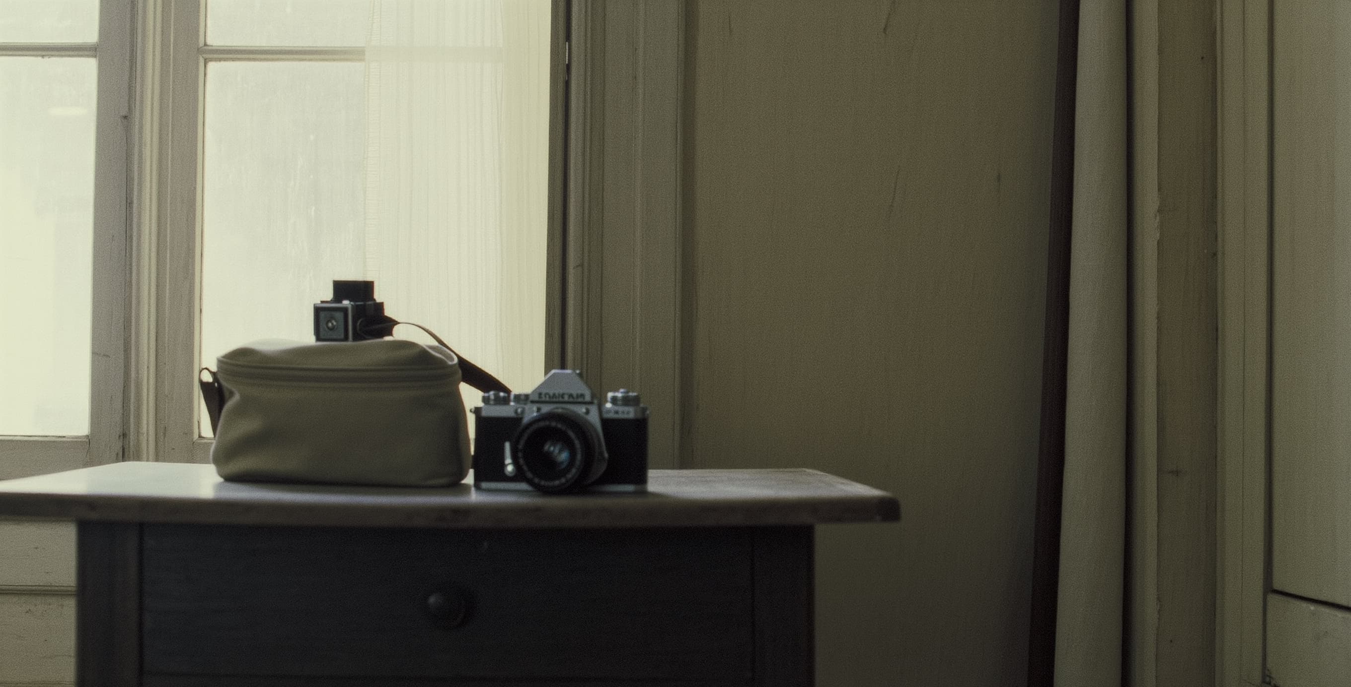 Wedding photographer's camera bag and film camera on windowsill with soft natural light