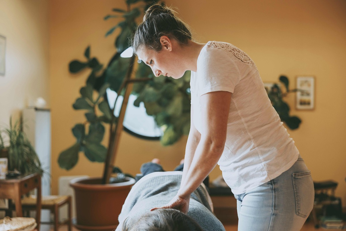 Elvire Nicolas, chiropracteur, effectuant un ajustement manuel sur le dos d’une patiente, visant à soulager les douleurs et à améliorer l’alignement vertébral dans un environnement de soin apaisant.