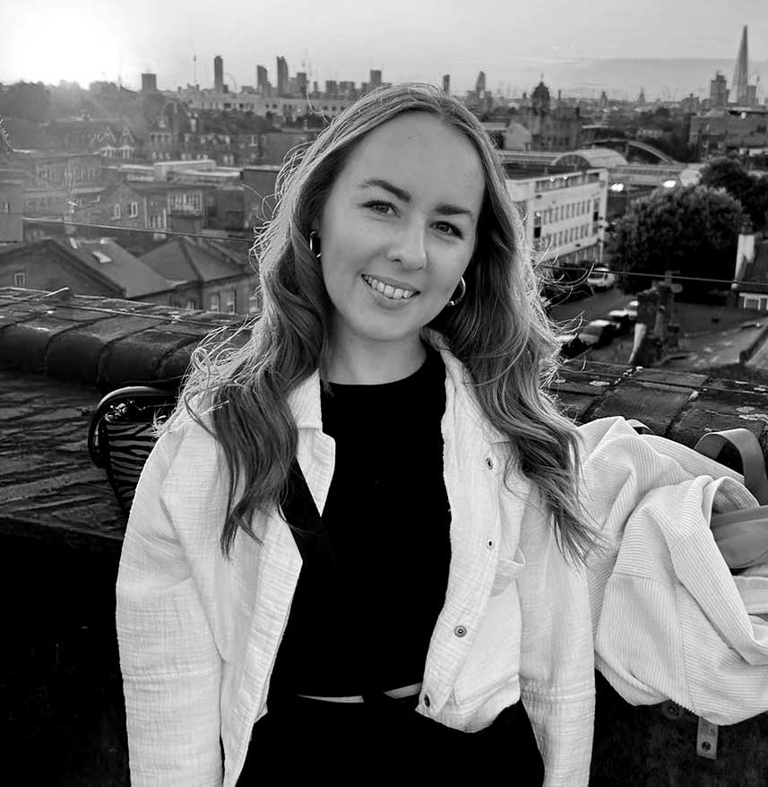 A thoughtful young person with dark hair gazes to the side, captured in soft black and white lighting.