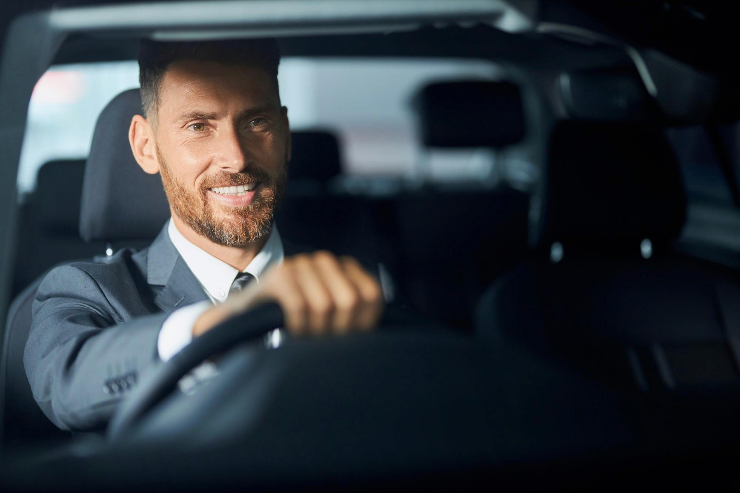 Spacious, luxurious living room with high ceilings, an elegant beige sectional sofa, warm ambient lighting, classical artwork, and rustic architectural elements, featuring an open layout with a view of a mezzanine level.