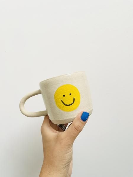 Light-colored mug with a yellow smiley face