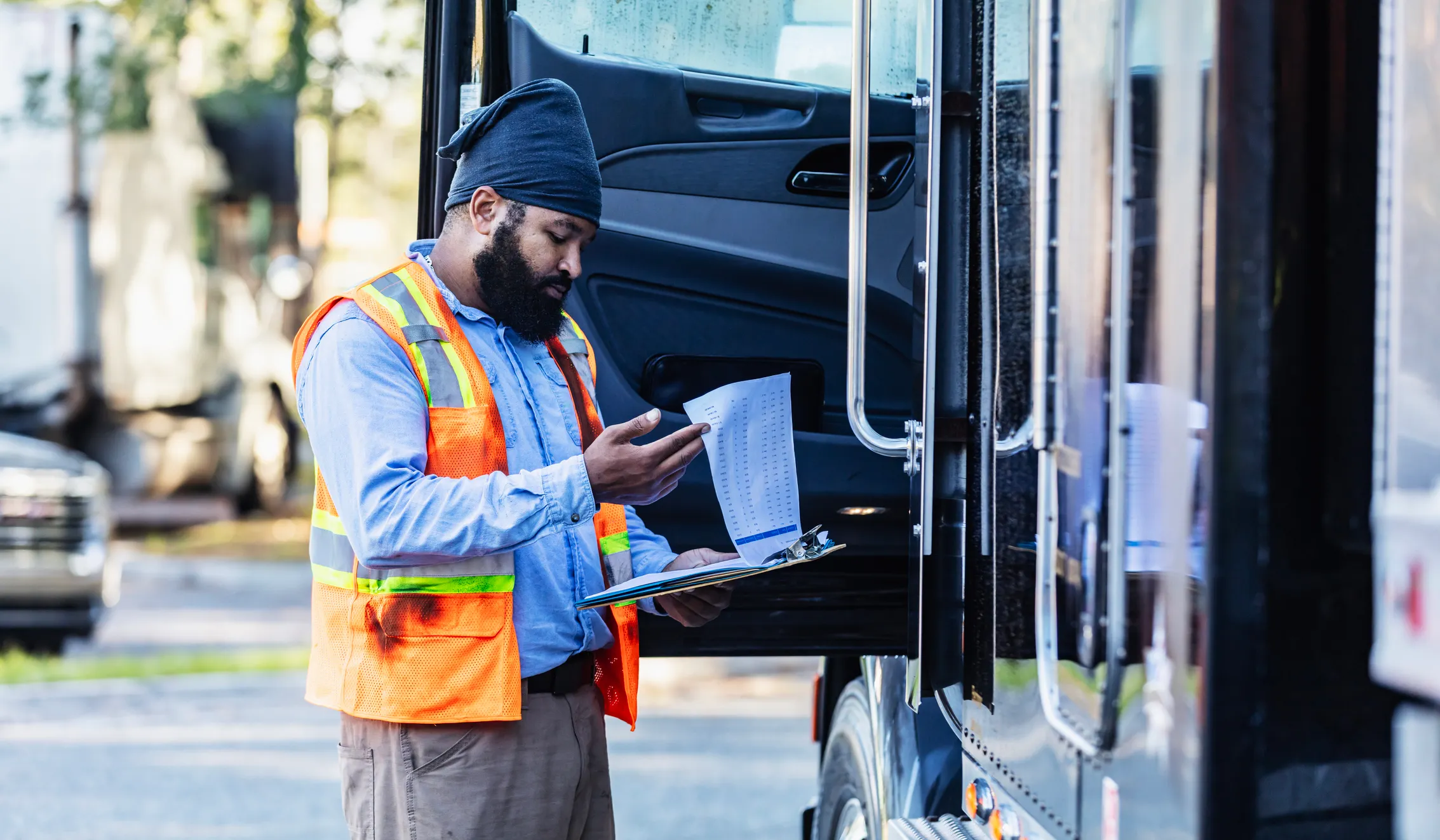 Commercial truck driver checking driver qualification and safety documents as part of FMCSA compliance requirements in the U.S. trucking industry.