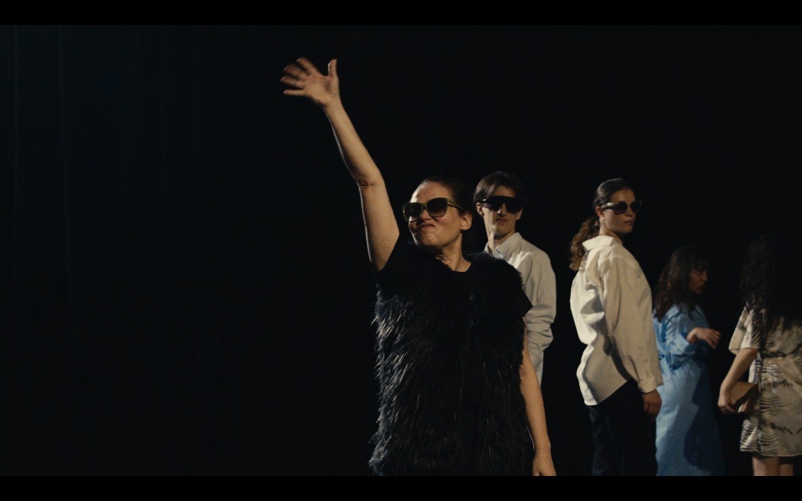 Woman in pink leather jacket crouching outdoors at night