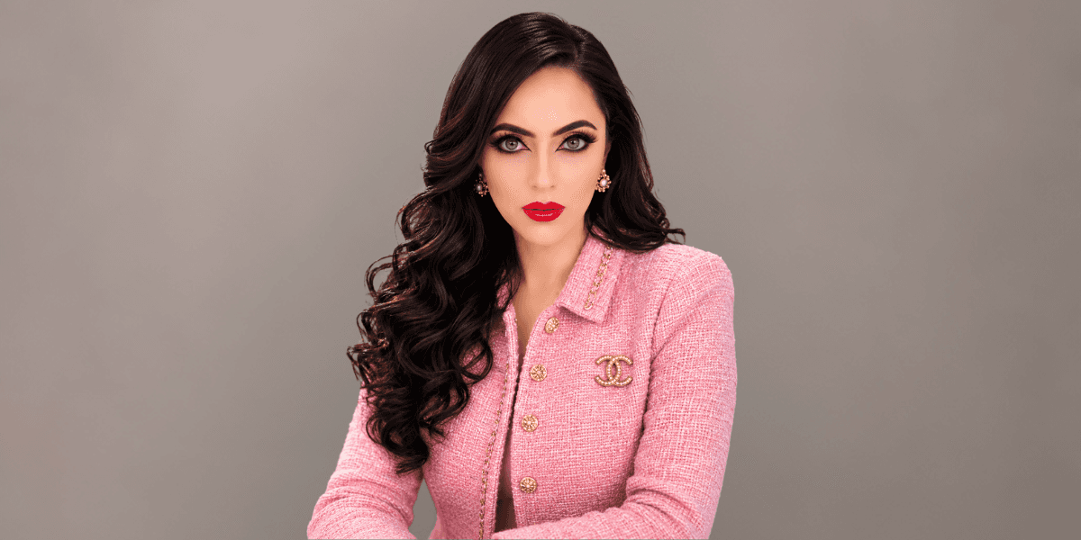 Professional portrait of hospitality entrepreneur Ashka Patel, CEO and hotel owner, in a pink blazer.