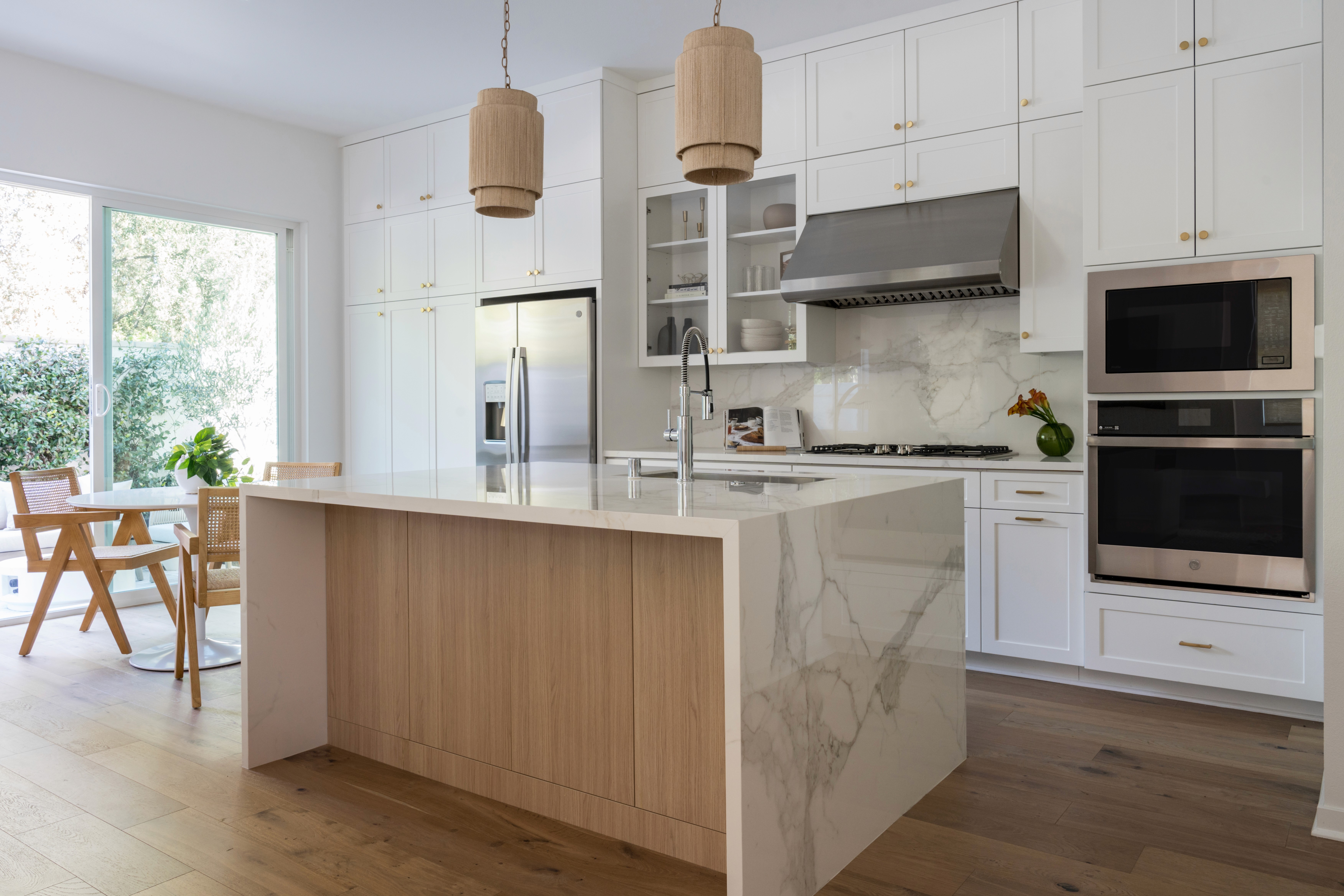 Bright kitchen with white cabinetry, wood tones, and marble countertops by Jubilee Interiors in Arcadia, California