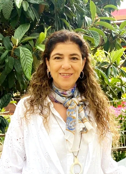 סמדר עציץ המנהלת מאבחנת ומטפל של נעים ולומדים בחולצה לבנה עם רקע של גינה ירוקה