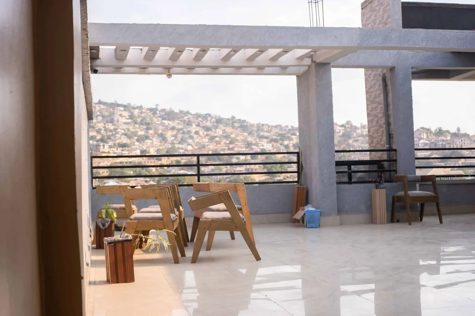 Terrasse couverte avec tables et chaises en bois face aux collines de Matadi.