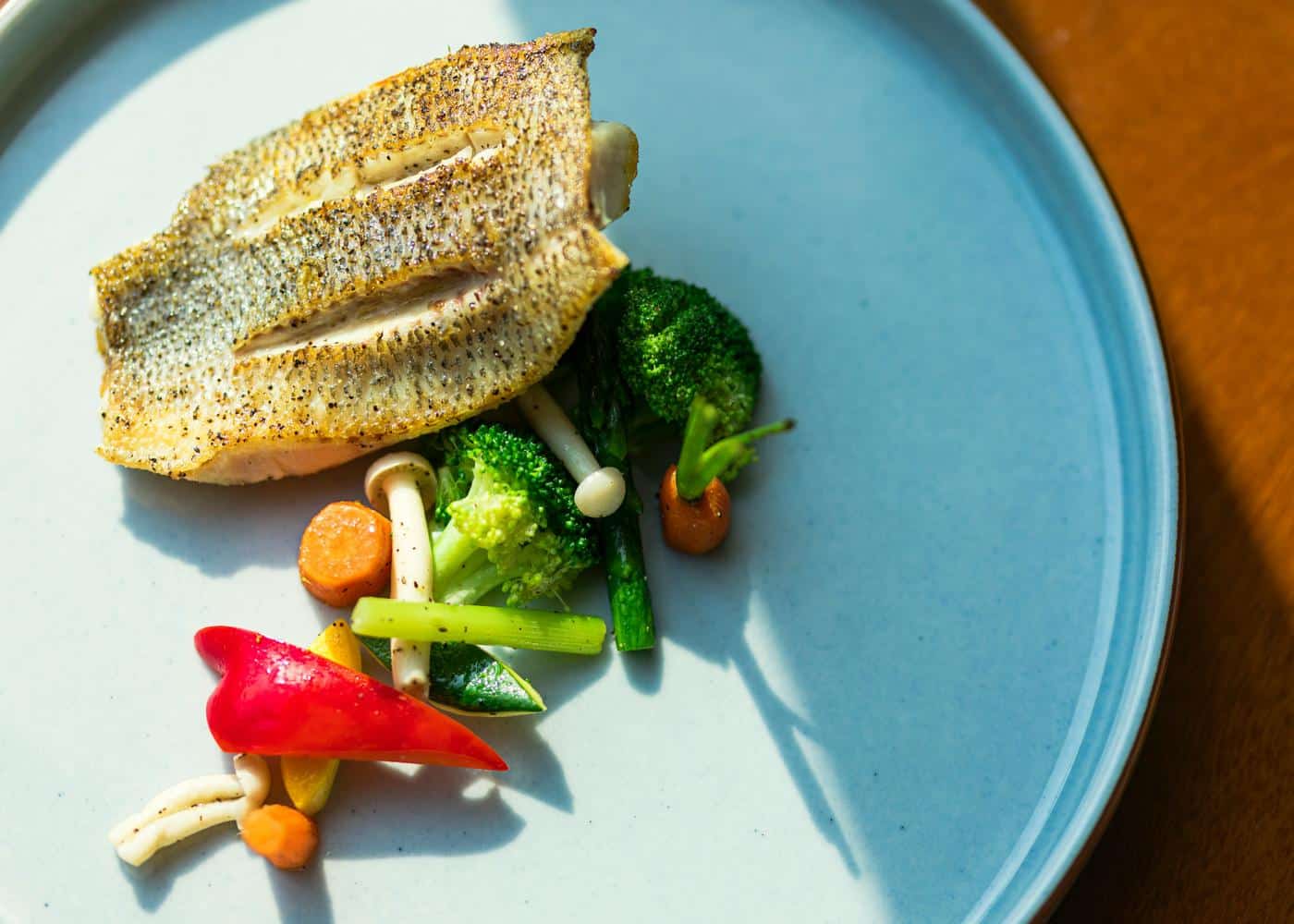 Grilled fish and vegetables on a light blue plate to showcase the caveman diet