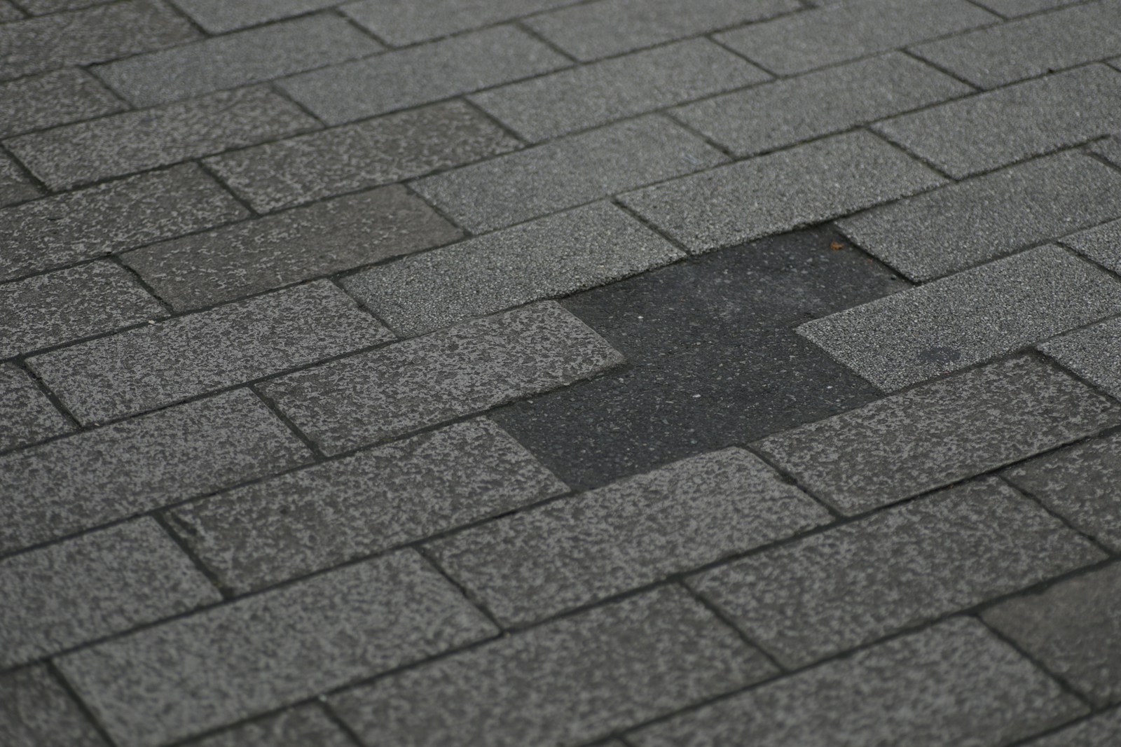 Close-up of an asphalt shingle roof with hail damage and missing shingles