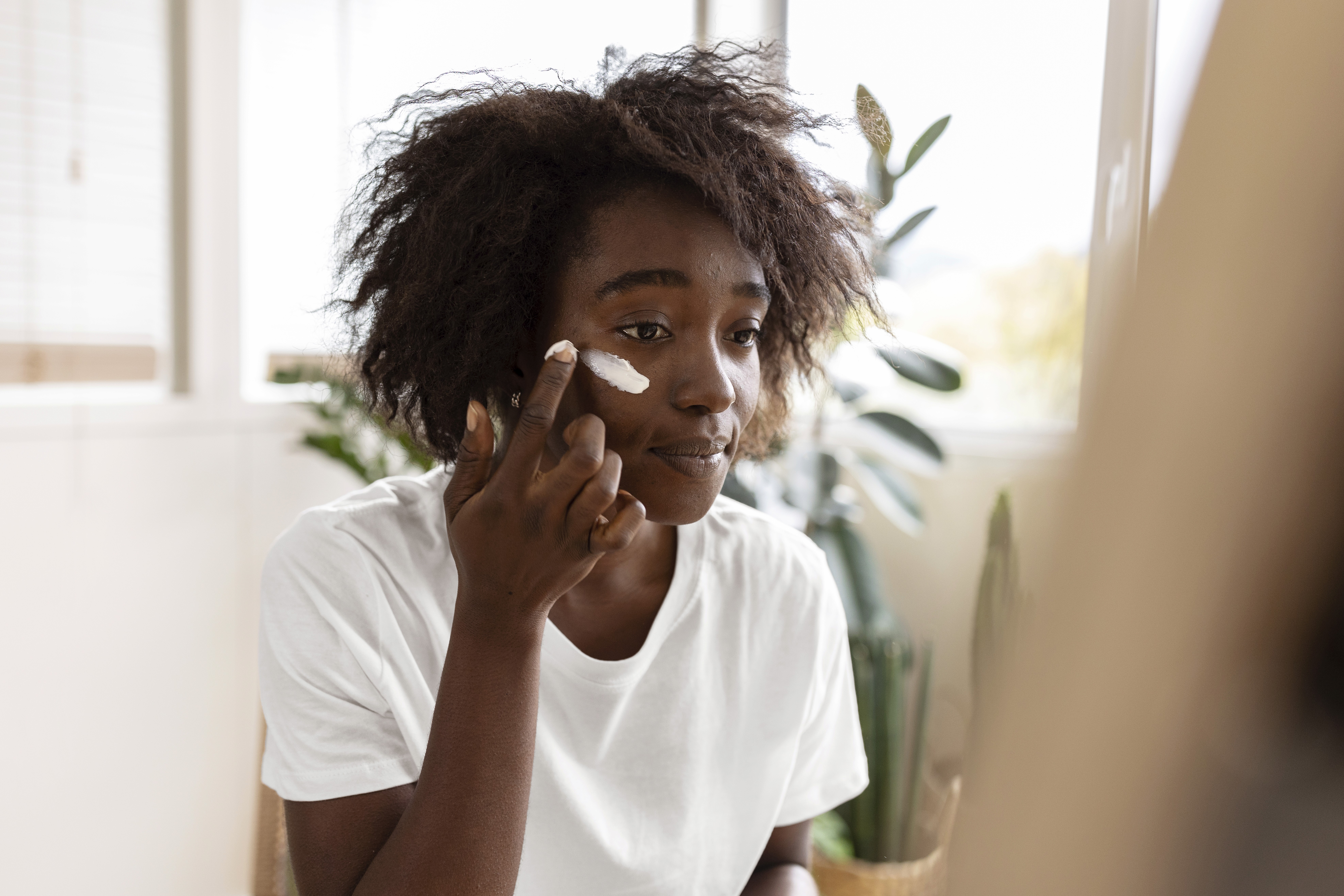 Woman applying cream in the mirror