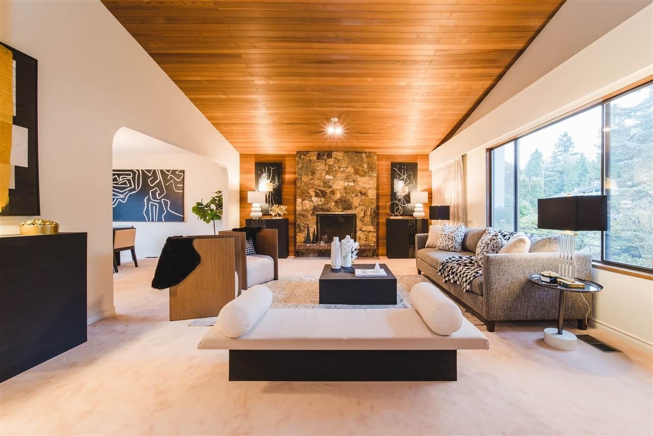 Modern interior with a wooden ceiling, stylish furniture, and large windows allowing natural light.