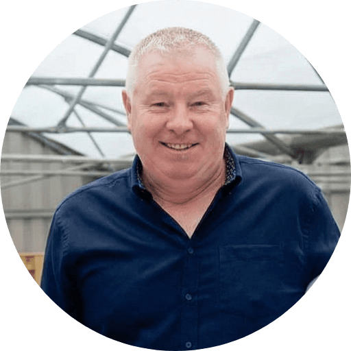 A person wearing the grey coat smiling in a cozy sunlight