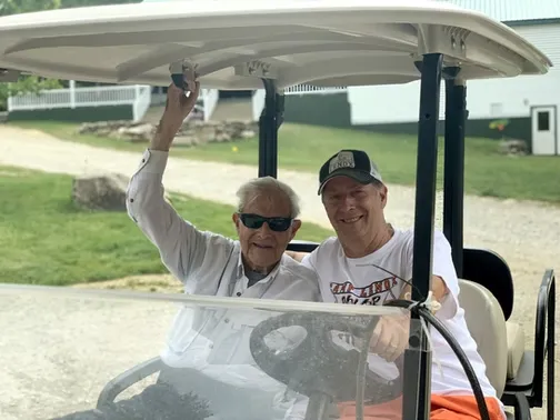 Rich Moss and Monty "Coach" Moss riding a golf cart together