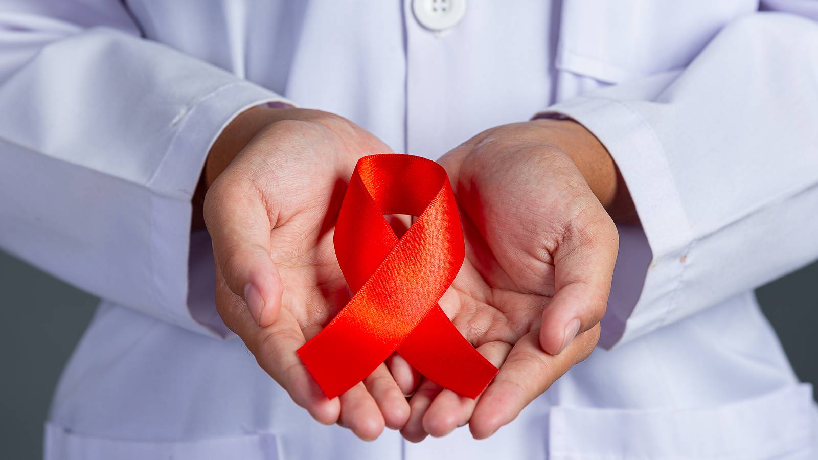 Médico com laço vermelho em mãos