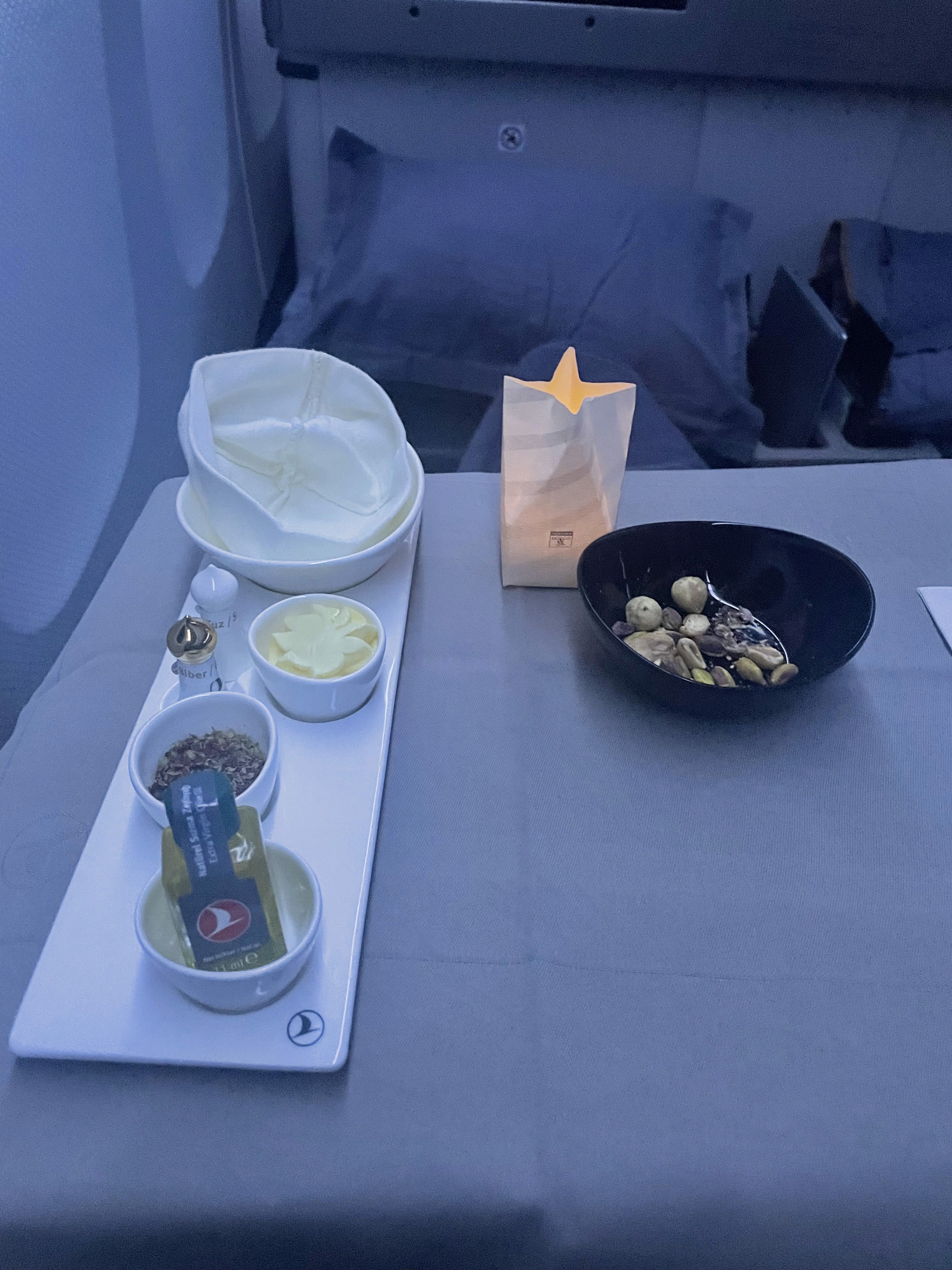 Foto real de cabine e serviço de bordo em classe executiva na Turkish Airlines, com refeição servida durante o voo.