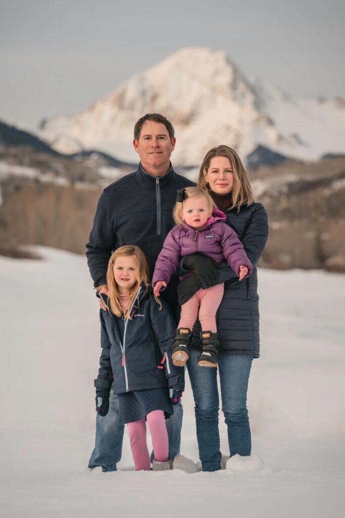 Family of four posing together in a snowy mountain landscape