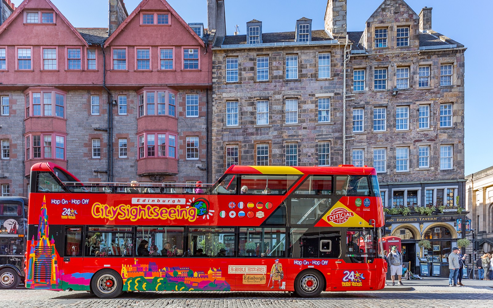 Edinburgh hop-on hop-off bus passing by historic city landmarks.