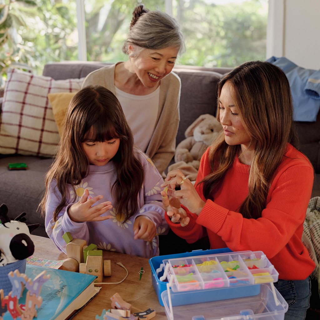 Happy family holding their small child and smiling at the child.