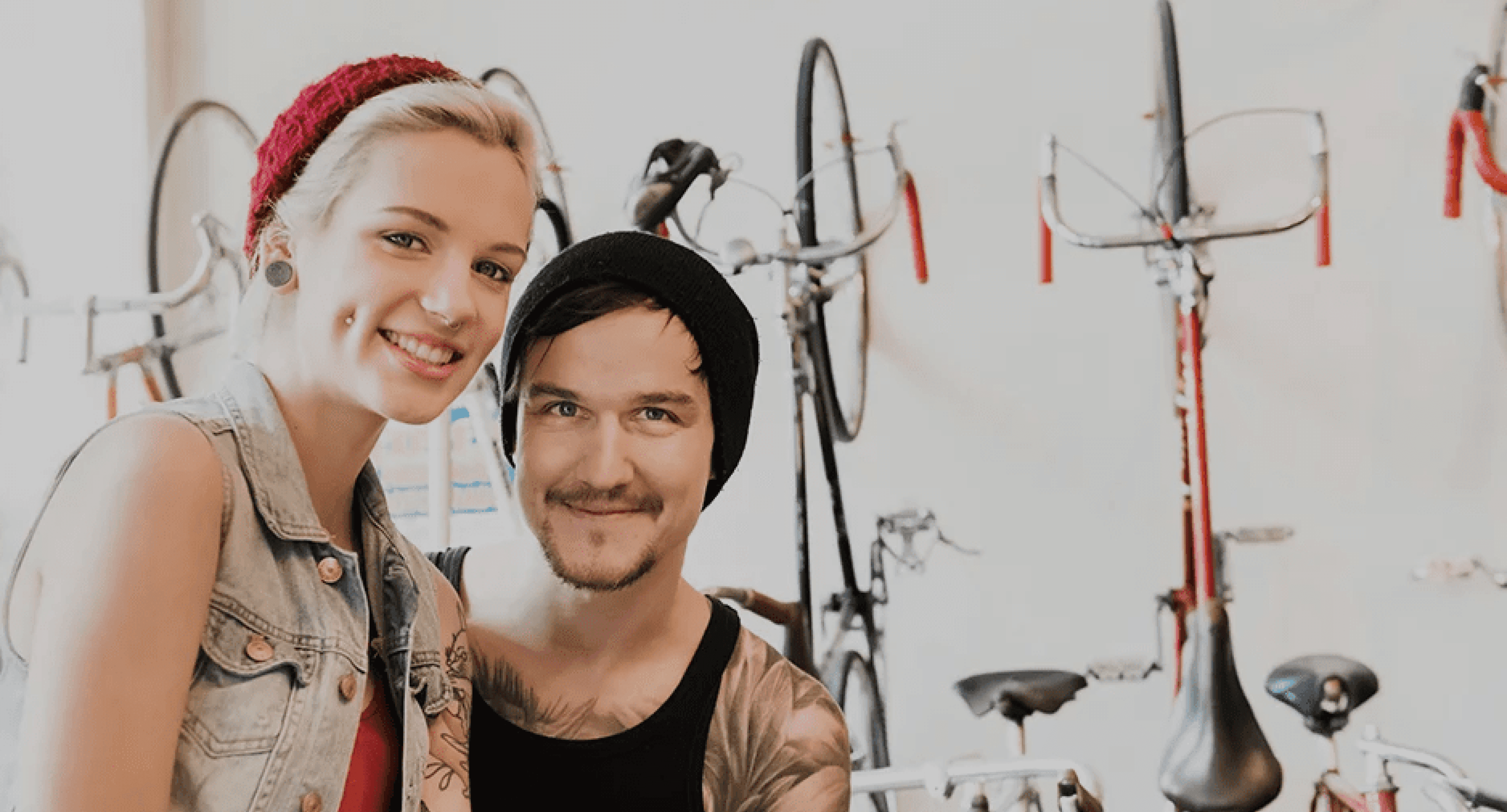 The owners of City Cycles sit and smile in front of a selection of bikes.