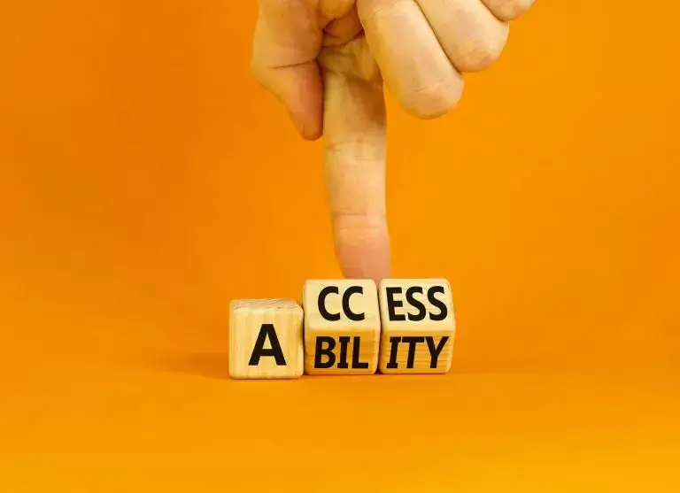 Image of three wood cubes on an orange floor. One cube has the letter A on it, the other two have CC and ESS on, a hand is flipping up the two CC and ECC cubes