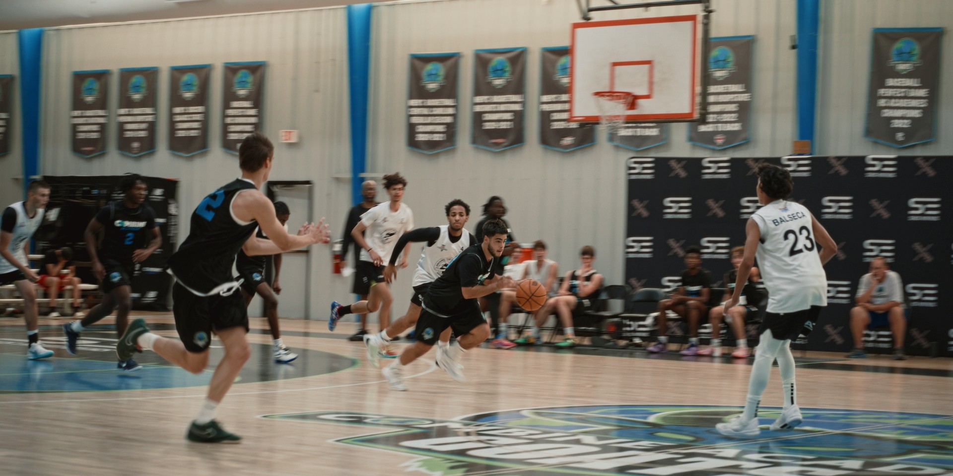 Action rapide sur le terrain durant un match de basket à la Combine Academy.