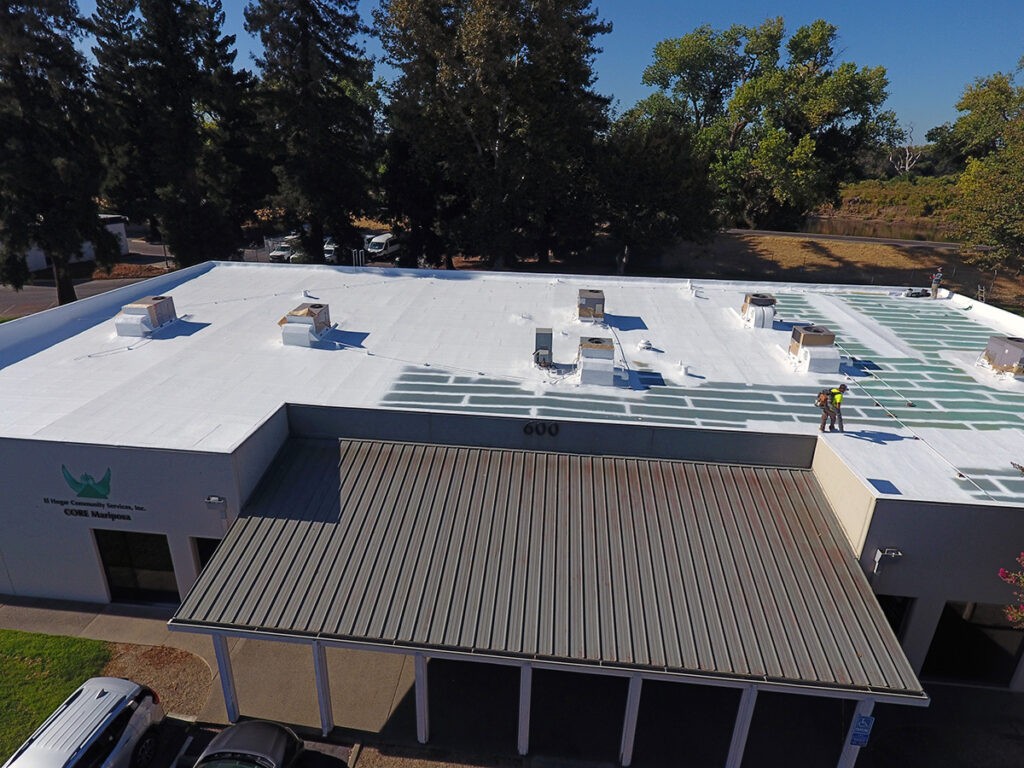 Commercial roof in process of Silicone & Acrylic roof restoration with RAD Systems team members working.